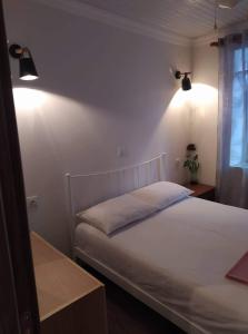 1 Schlafzimmer mit einem weißen Bett und 2 Leuchten in der Unterkunft Vasilis traditional House in Samothráki