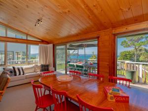 a living room with a wooden table and chairs at Beachfront Views - Hahei Holiday Home in Hahei