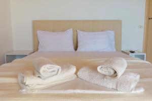 a bed with two towels and two pillows on it at Alex & Sofi Apartments in Himare