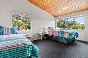 two beds in a room with two windows at Country Retreat - Athenree Holiday Home in Waihi Beach