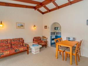 a living room with a couch and a table and chairs at Oyster Bach - Cooks Beach Bach in Cooks Beach