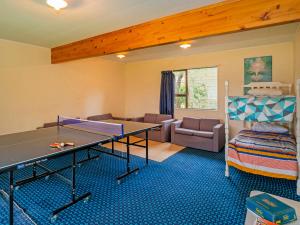 a room with a ping pong table and a living room at Oyster Bach - Cooks Beach Bach in Cooks Beach