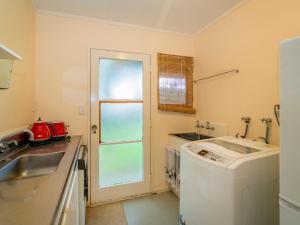 a kitchen with a sink and a washing machine at Oyster Bach - Cooks Beach Bach in Cooks Beach +20 photos