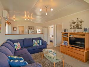 a living room with a blue couch and a glass table at Breakaway - Tairua Bach in Tairua