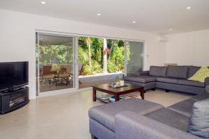 a living room with a couch and a tv and a table at Paradise at Pauanui - Pauanui Holiday Home in Pauanui