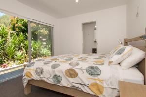 a bedroom with a bed and a large window at Paradise at Pauanui - Pauanui Holiday Home in Pauanui