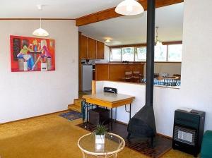 a living room with a kitchen with a stove in it at Hibiscus Cottage - Whangamata Bach in Whangamata