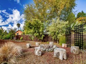 a garden with logs and a fence and trees at Stag & 3 Pigs - Ohakune Holiday Home in Ohakune