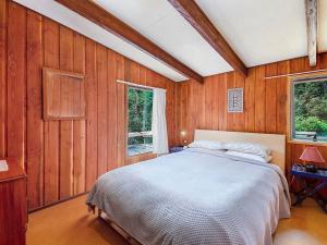 una camera da letto con pareti in legno e un letto interno di Te Kuru Cabin - Pukawa Bay Holiday Home a Kuratau
