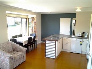 a kitchen and living room with a couch and a table at The Sands - Matarangi Holiday House in Matarangi