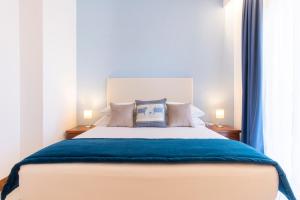 a bedroom with a large bed with blue sheets and pillows at Best Western Hotel Blumarea in Castelsardo