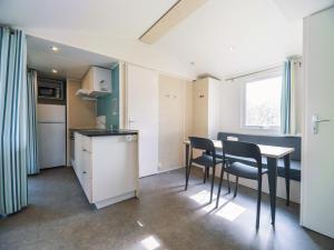 a kitchen with a table and chairs in a room at Camping Paradis 4 étoiles A La Corniche La Rochelle Angoulins in Angoulins-sur-Mer