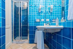 a blue tiled bathroom with a sink and a shower at Best Western Hotel Blumarea in Castelsardo