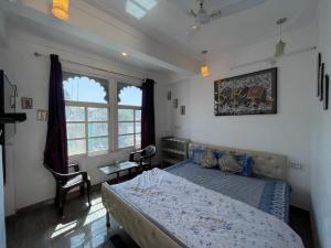 a bedroom with a bed and a chair and a window at Boraj Haveli Guest House in Udaipur