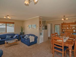a living room with a blue couch and a table at Wonderful Whangamata - Whangamata Holiday Home in Whangamata