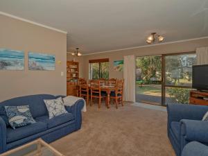 a living room with a blue couch and a dining room at Wonderful Whangamata - Whangamata Holiday Home in Whangamata
