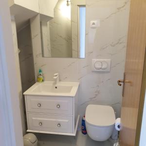 a white bathroom with a sink and a toilet at Aparthotel Marina in Primošten +37 photos