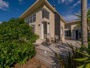 Casa con terraza con mesa y sillas en Golfers and Beach Lovers Dream - Matarangi House, en Matarangi