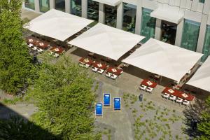 una vista aérea de un edificio con mesas y sombrillas blancas en H2 Hotel München Messe, en Múnich