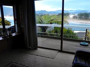 a room with a door open to a view of a beach at The Great Escape - Tairua Holiday Home in Tairua