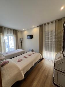 a bedroom with two beds and a television in it at Time Holiday´s House in Olhão