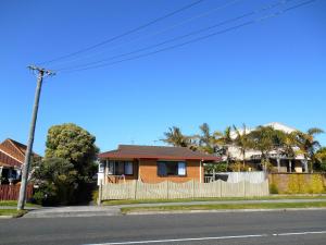 a house on the side of a street with a fence at At The Mount - Mt Maunganui Holiday Home in Mount Maunganui