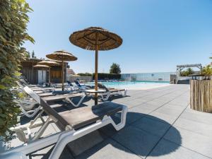 - un groupe de chaises longues et de parasols à côté de la piscine dans l'établissement Camping 4 étoiles Au Petit Port de L'Houmeau - La Rochelle, à LʼHoumeau