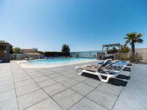 a row of lounge chairs next to a swimming pool at Camping Paradis 4 étoiles Au Port de L'Houmeau - La Rochelle in LʼHoumeau