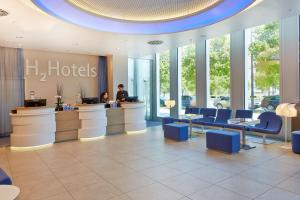 a lobby of a hotel with people at a counter at H2 Hotel München Messe in Munich