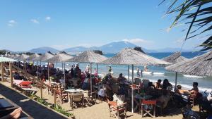 a group of people sitting on a beach with umbrellas at PiPi's House in Nea Artaki