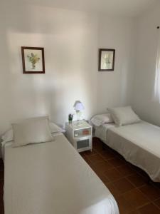 タリファにあるFinca Dos Vientos Tarifaのベッド2台、テーブル(ランプ付)が備わる客室です。