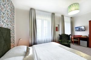 a hotel room with a bed and a desk at APLEND Hotel Lujza Major in Tatranská Lomnica