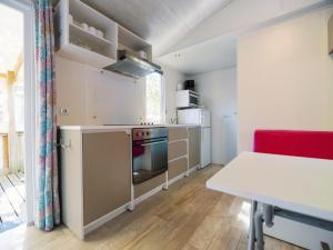 a small kitchen with a table and a red chair at Camping Paradis 4 étoiles Au Port de L'Houmeau - La Rochelle in LʼHoumeau