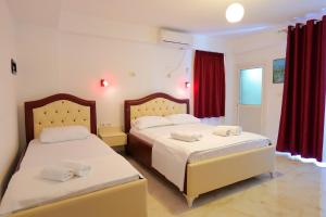 two beds in a room with red curtains at Vila Ani in Ksamil