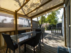 a patio with a table and chairs on a deck at Camping Paradis 4 étoiles Au Port de L'Houmeau - La Rochelle in LʼHoumeau