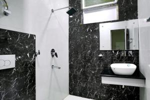 a black and white bathroom with a sink and a mirror at Hotel Surya Lake view in Nainital
