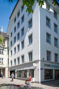 a white building with a woman standing in front of it at Boutique Hotel Helmhaus Zürich in Zurich