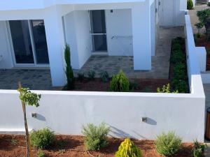 a front yard of a house with a white wall at Gardenhouse 4 in Pilalímata