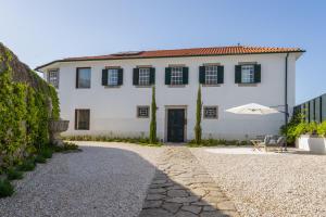 a white house with a table and an umbrella at FONTE SANTA Manor House in Vila Nova de Gaia