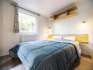 a bedroom with a large bed with a blue blanket at Camping Paradis 4 étoiles Au Port de L'Houmeau - La Rochelle in LʼHoumeau