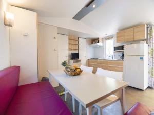 a kitchen with a table with a bowl of fruit on it at Camping Paradis 4 étoiles Au Port de L'Houmeau - La Rochelle in LʼHoumeau