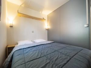 a small bedroom with a bed with blue sheets at Camping Paradis 4 étoiles Au Port de L'Houmeau - La Rochelle in LʼHoumeau