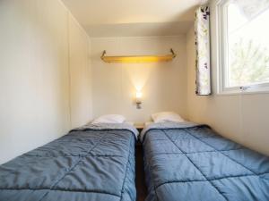 two beds in a small room with a window at Camping Paradis 4 étoiles Au Port de L'Houmeau - La Rochelle in LʼHoumeau