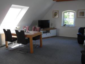 una sala da pranzo con un tavolo con sedie e una televisione di Landhaus Martina a Krummhörn