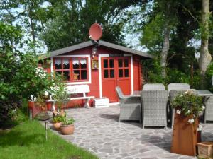 un capanno rosso con sedie e un patio di Landhaus Martina a Krummhörn