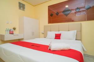 a bedroom with a large white bed with a red blanket at RedDoorz Plus Syariah near Pasar Turi in Kandangsapi