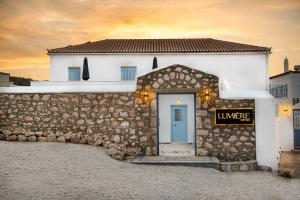 um edifício branco com uma porta azul numa parede de pedra em Lumiére spetses em Spetses