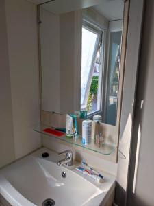 a bathroom sink with a mirror and a window at KERLANN 4 ETOILES MOBIL HOME 3 CHS 1 SDB Pont aven in Pont-Aven