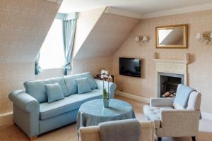 a living room with a blue couch and a fireplace at Roman Camp Country House Hotel in Callander