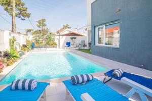 una piscina con 2 sillas azules junto a una casa en Villa Santi, en Aroeira